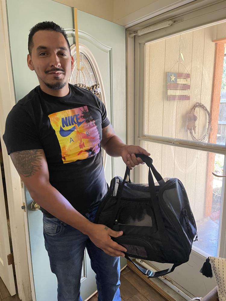 Man holding a black pet carrier bag.